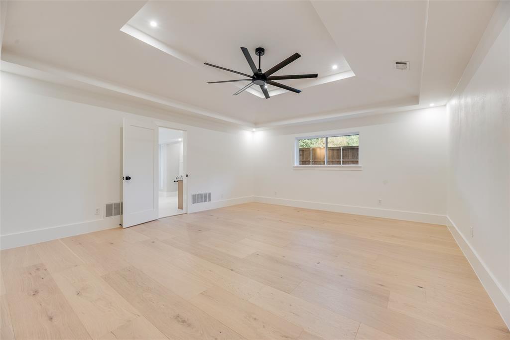 Tray ceiling with recessed lighting, matte black multi-blade ceiling fan, wood-finish flooring, and shaker-style interior door