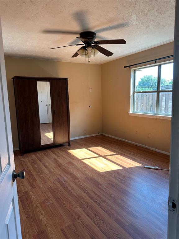 Wood-finish flooring, multi-pane window, and ceiling-mounted fan with integrated light fixture