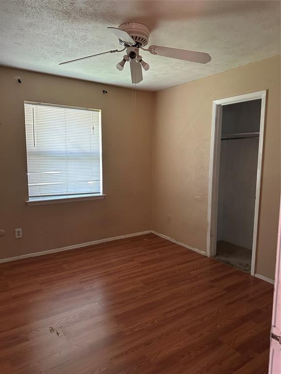 Interior space featuring wood-finish flooring, a ceiling fan with integrated lighting, and a closet with an overhead shelf