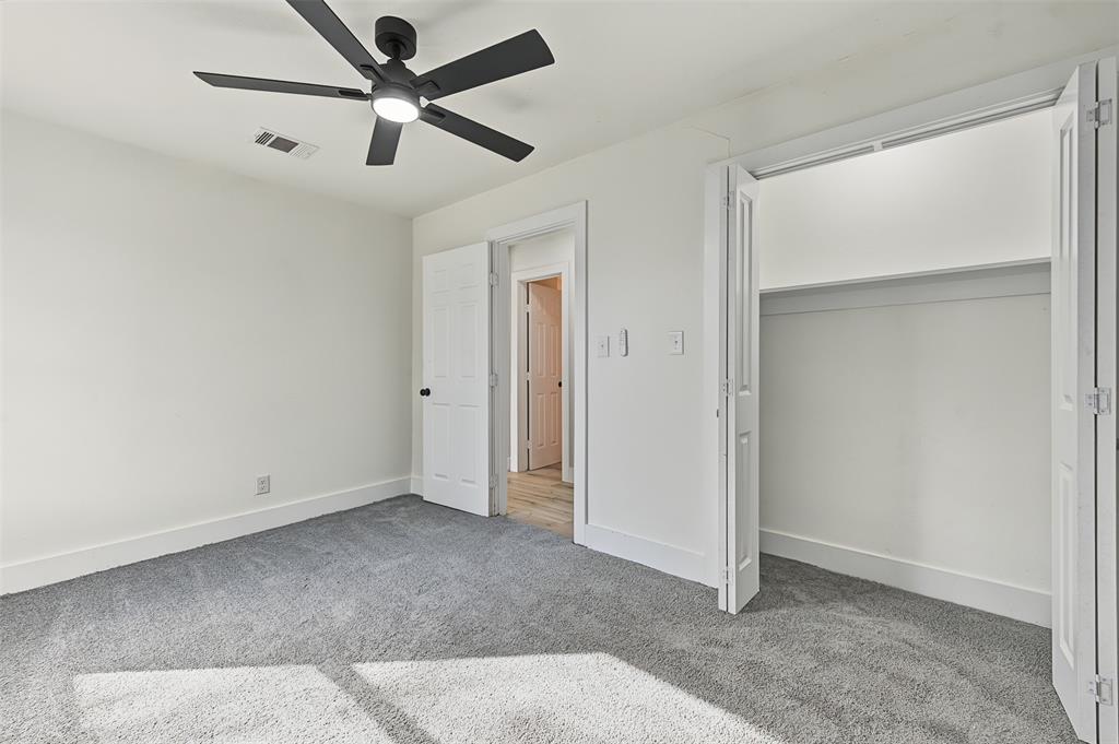 Interior space featuring wall-to-wall carpeting, matte black multi-blade ceiling fan with integrated lighting, and white six-panel interior doors
