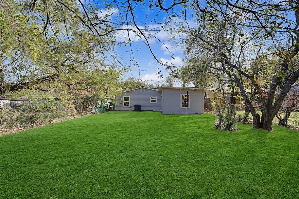 Expansive backyard featuring a level lawn, mature trees, and perimeter fencing