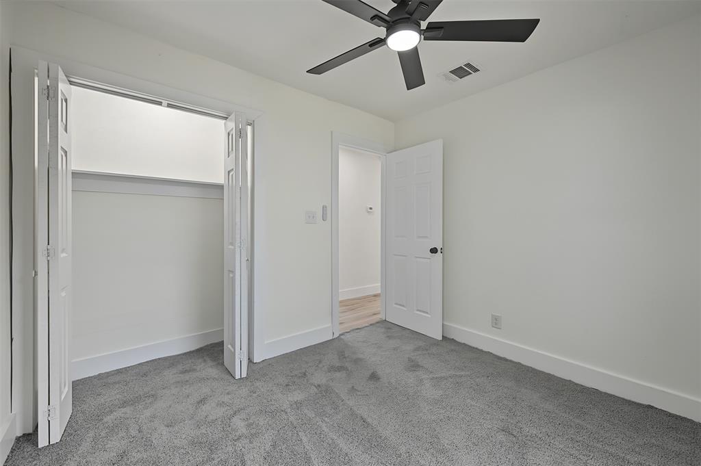 Interior space featuring wall-to-wall carpeting, a multi-blade ceiling fan with integrated lighting, a dual-paneled closet door, and a solid-core interior door