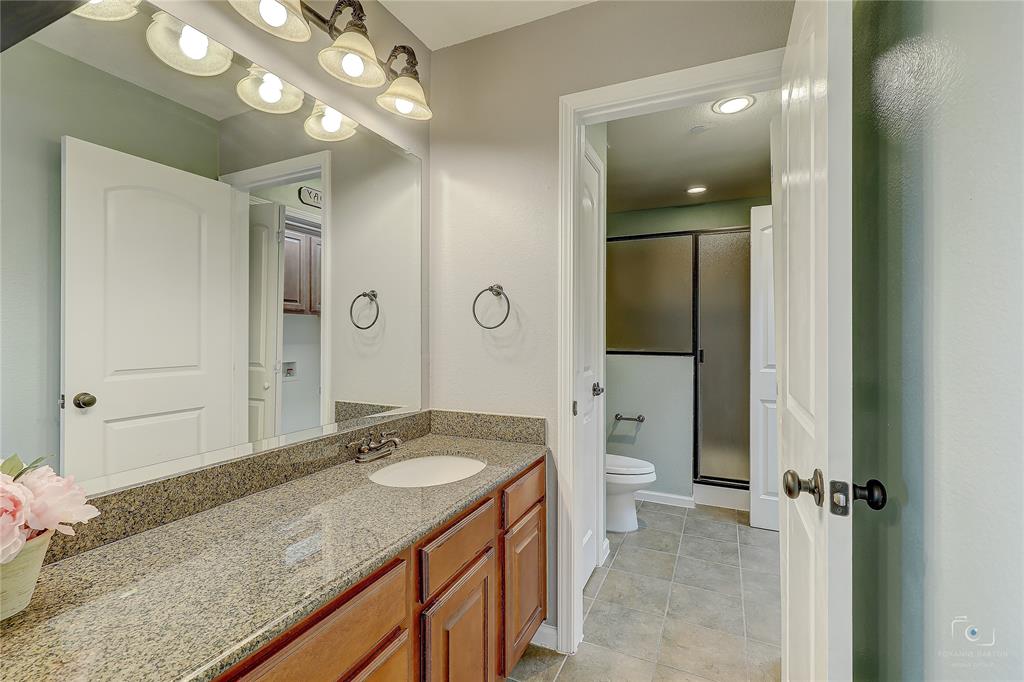 Bathroom featuring a vanity with stone-finish countertop, undermount sink, overhead multi-bulb lighting, and tile flooring