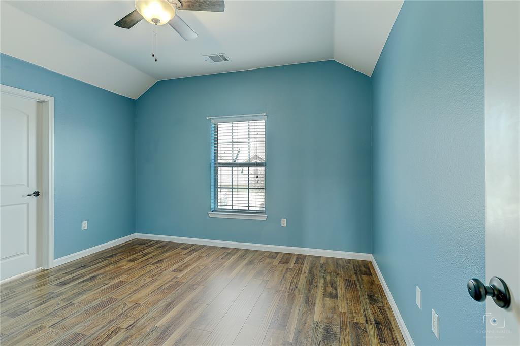 Vaulted ceilings, wood-finish flooring, and single-hung window with blinds, complemented by a ceiling fan with integrated lighting