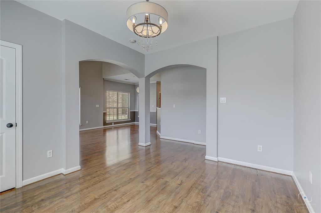 Wood-finish flooring, architectural arched openings, and a drum-style chandelier with crystal accents