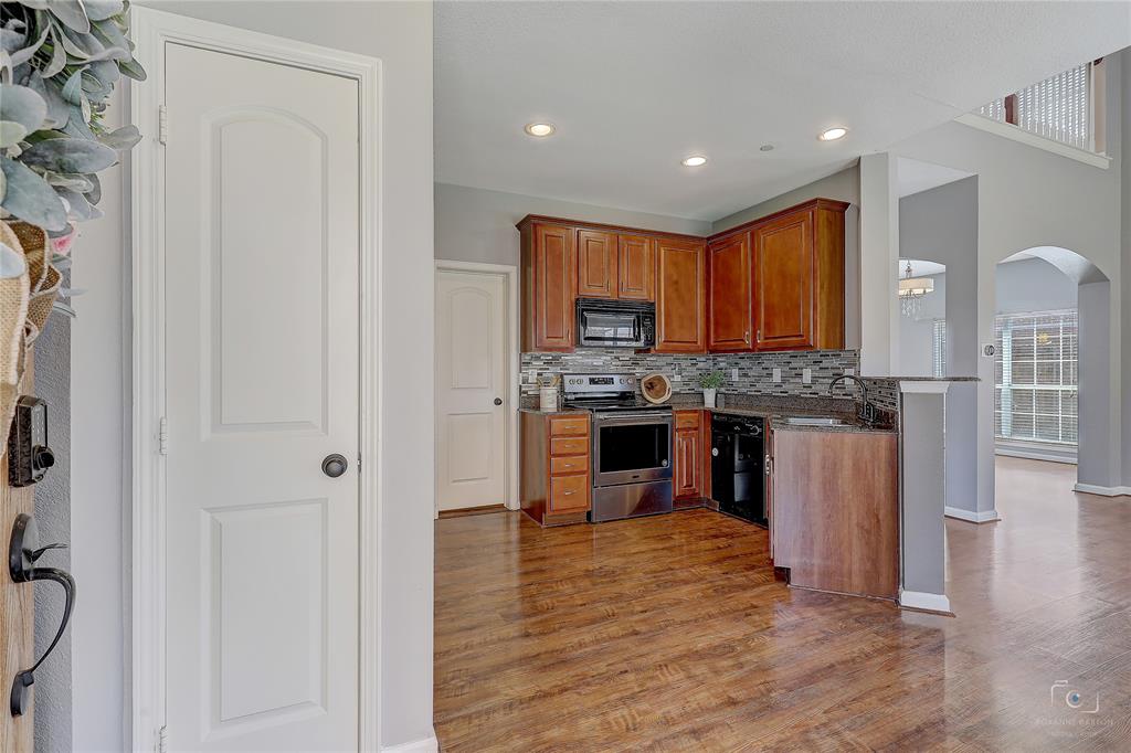 Kitchen featuring wood cabinetry, stainless steel appliances, a multi-tonal tile backsplash, recessed lighting, and wood-finish flooring