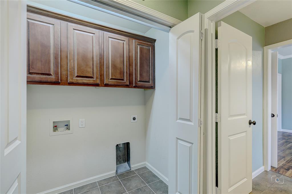 Dedicated utility space featuring stained wood cabinetry, tile flooring, and arched-panel interior doors