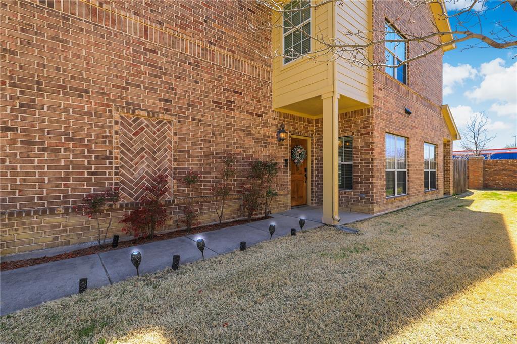 Multi-story brick exterior featuring herringbone masonry detailing, a concrete walkway, and a covered entryway