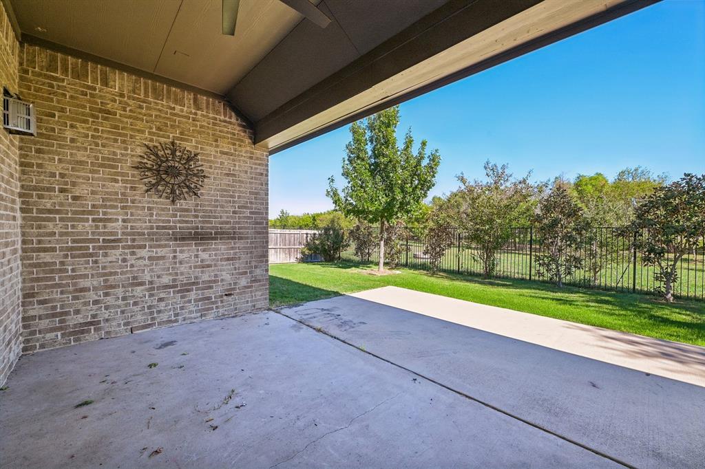 Covered brick patio featuring a concrete floor, recessed ceiling lighting, and a metal perimeter fence enclosing the backyard