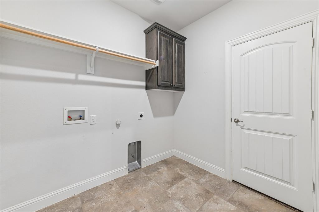Utility space featuring tile flooring, wall-mounted dark wood-finish cabinetry, a built-in hanging rod, and a multi-panel door