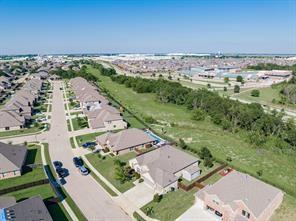 Aerial perspective of residential properties featuring brick-facade homes, multi-pitched shingle roofing, concrete driveways, and expansive greenbelt areas