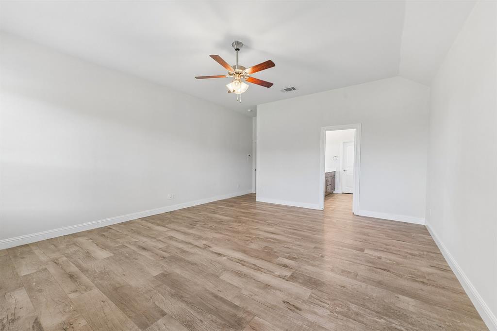 Vaulted ceilings featuring a centrally mounted ceiling fan with integrated lighting and neutral wood-finish flooring