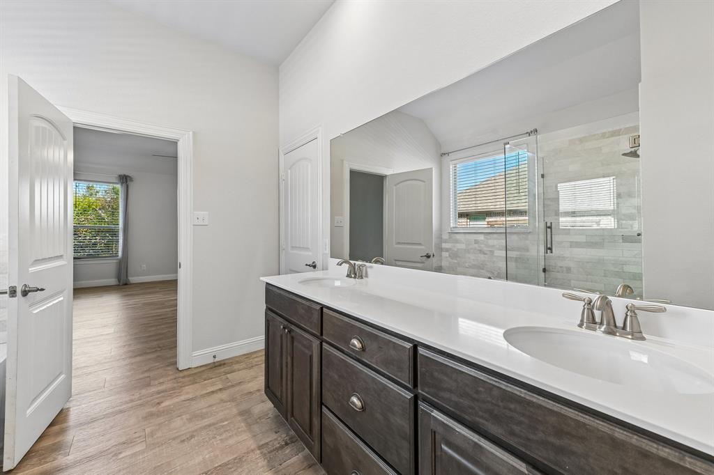 Bathroom vanity featuring dark-toned cabinetry, dual undermount sinks, and a solid-surface countertop with a full-width mirror