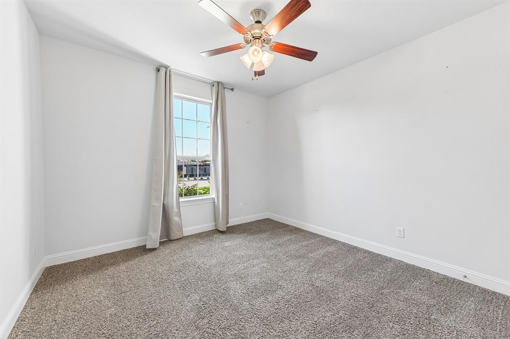 Neutral wall tones, wall-to-wall carpeting, window with grid panes, and ceiling fan with integrated light fixture