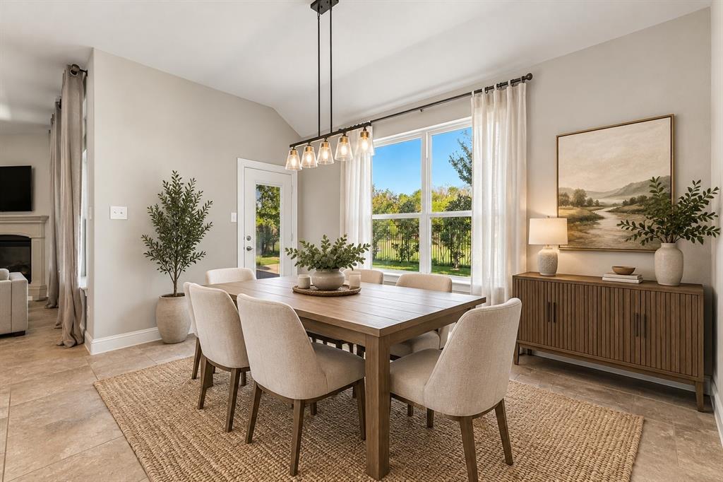 Dining space featuring vaulted ceilings, large multi-pane windows, a five-light linear pendant fixture, and neutral stone-finish flooring