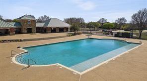 Rectangular swimming pool with built-in stairs, surrounded by a paved patio area and masonry building structure