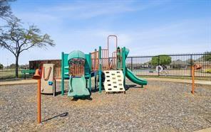 Playground structure featuring a slide, climbing wall, and metal safety fencing