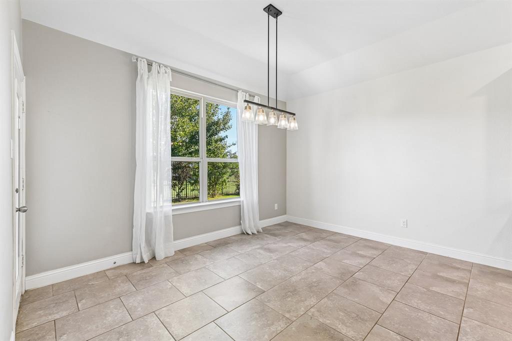 Room featuring large-format ceramic tile flooring, neutral wall paint, a multi-light linear chandelier, and a substantial window