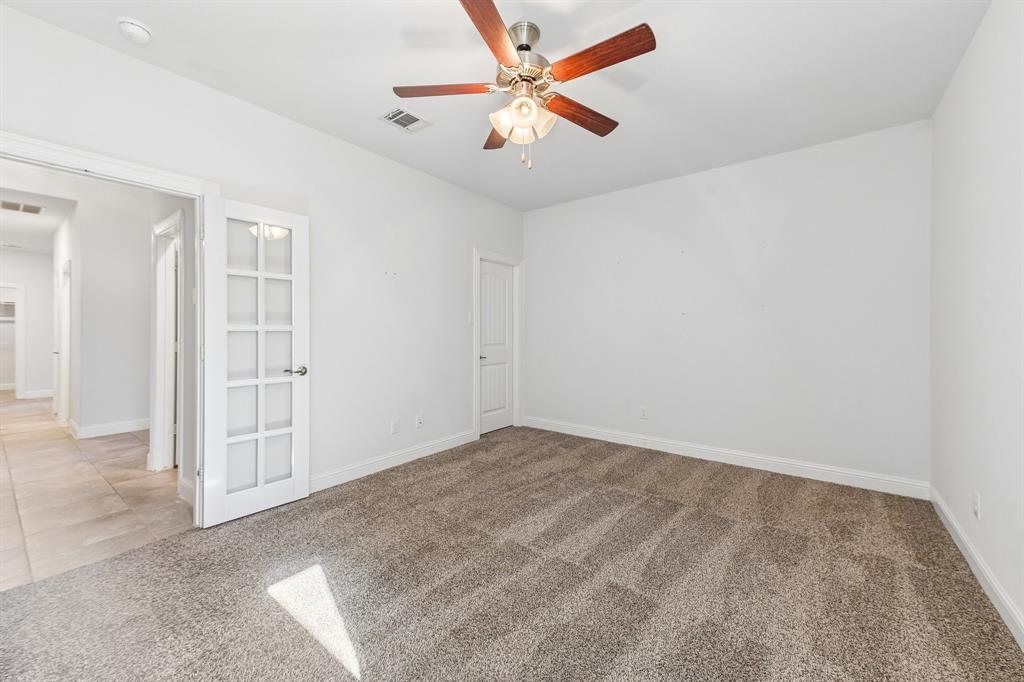 Neutral interior featuring wall-to-wall carpeting, a ceiling fan with integrated lighting, and a white French door with glass panels
