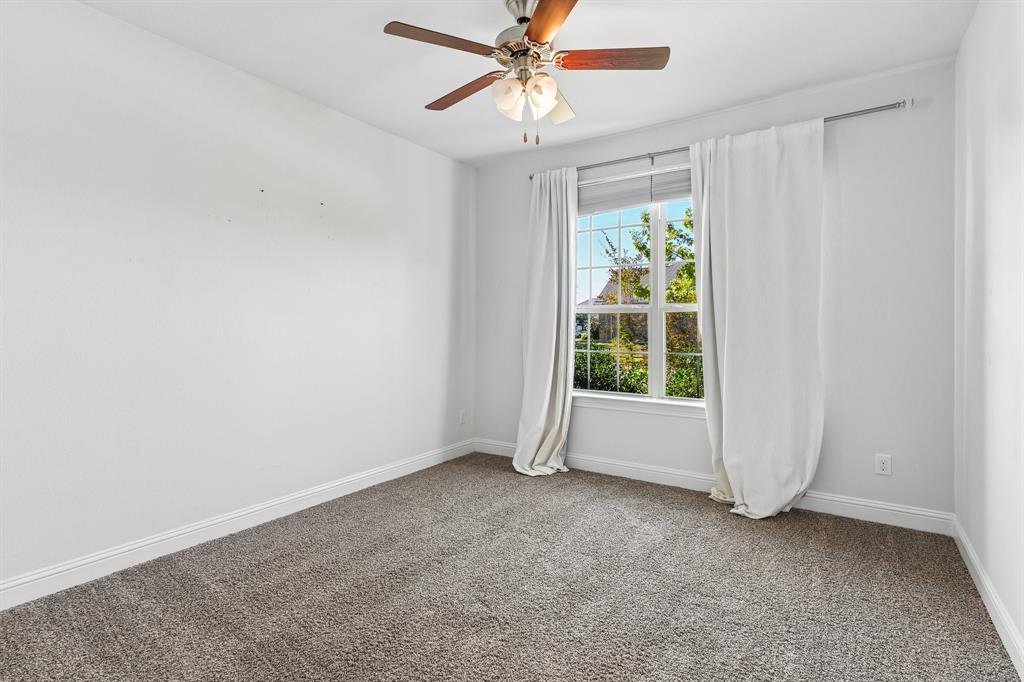 Neutral-toned carpeting, multi-pane window with natural light, and ceiling-mounted light fixture with wooden fan blades