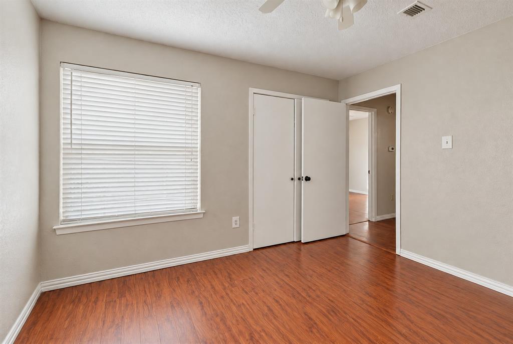 Room featuring wood-finish flooring, a neutral wall palette, a dual-panel closet door, and a horizontal slatted window blind