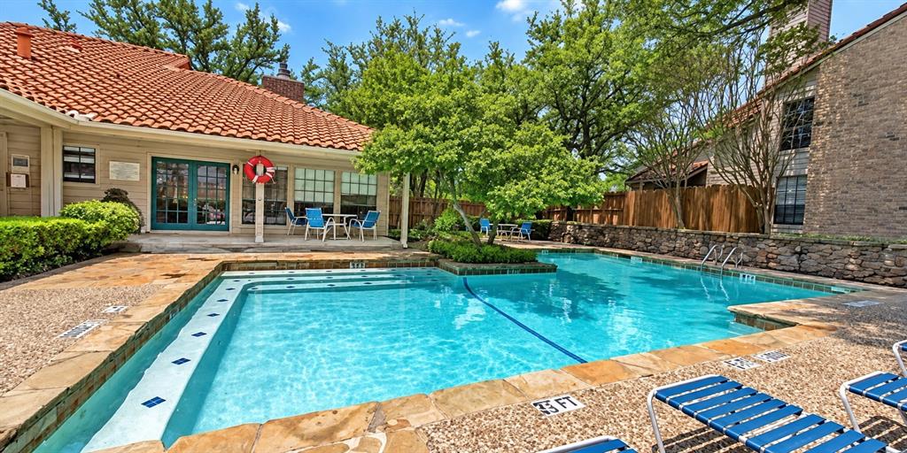 In-ground swimming pool featuring a stone-tile surround, built-in entry steps, and a decorative stone perimeter wall