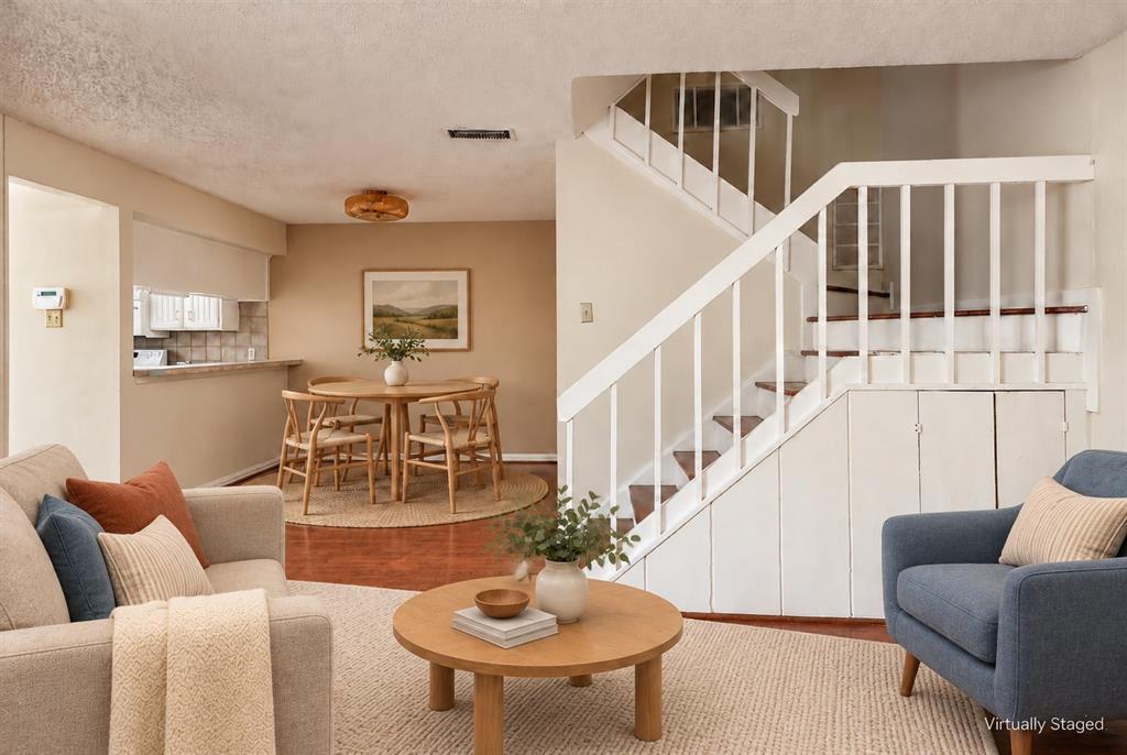 Open interior featuring wood-finish flooring, a staircase with white balusters, and built-in under-stair storage cabinetry