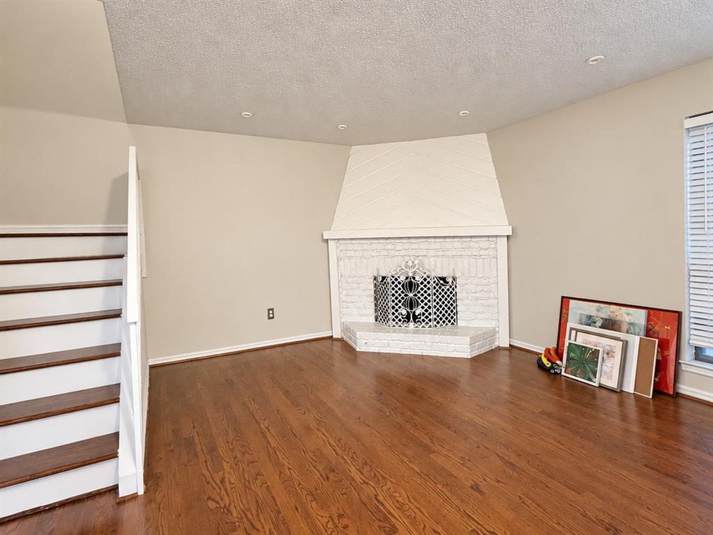 Corner fireplace with white painted brick surround and integrated geometric paneling, wood-finish flooring, and recessed ceiling lighting