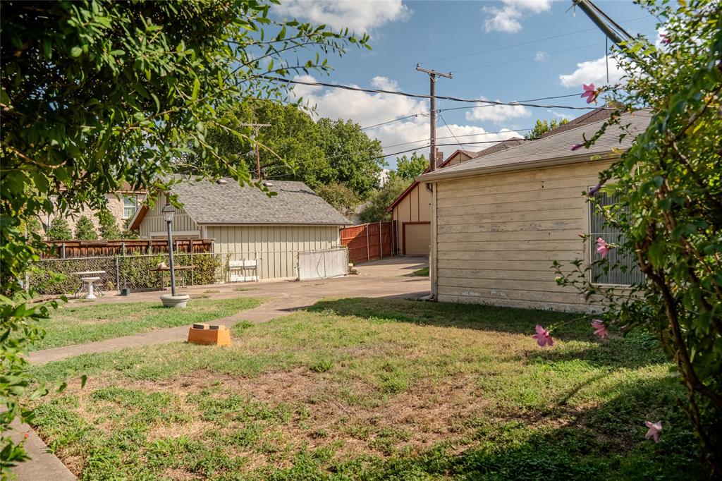 Exterior space featuring a concrete driveway, detached garage with horizontal siding, and perimeter wood fencing