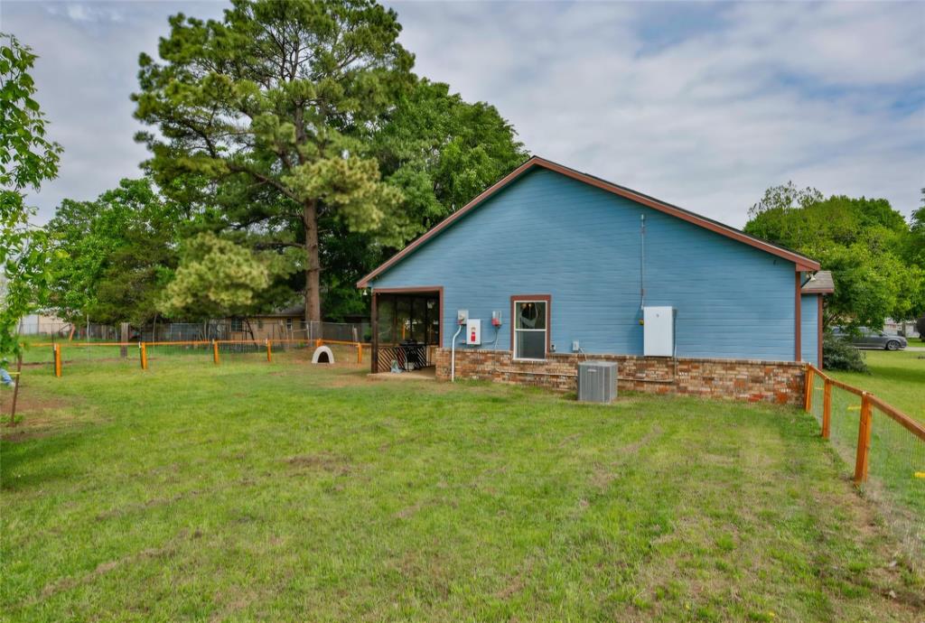 Exterior featuring horizontal lap siding, brick masonry, a fenced perimeter, and mature trees
