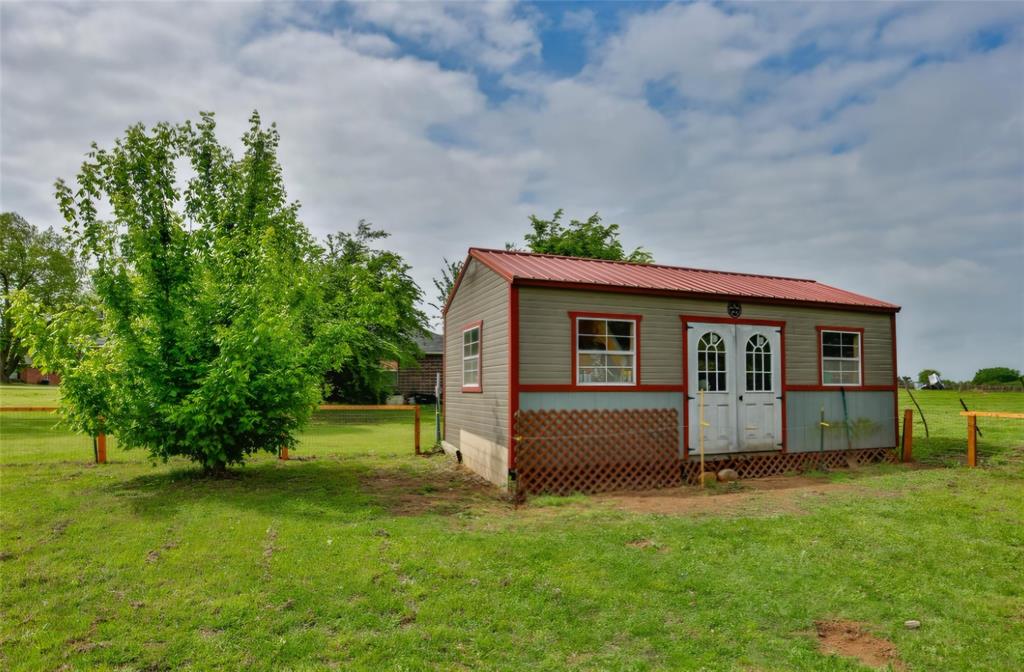 Detached storage building with metal roofing, vinyl siding, double entry doors, and lattice skirting, situated on a fenced lot
