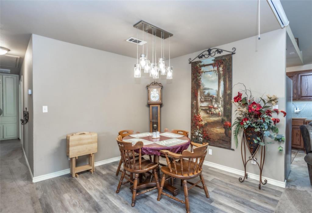 Multi-pendant light fixture with glass shades, wood-finish flooring, and neutral wall tones