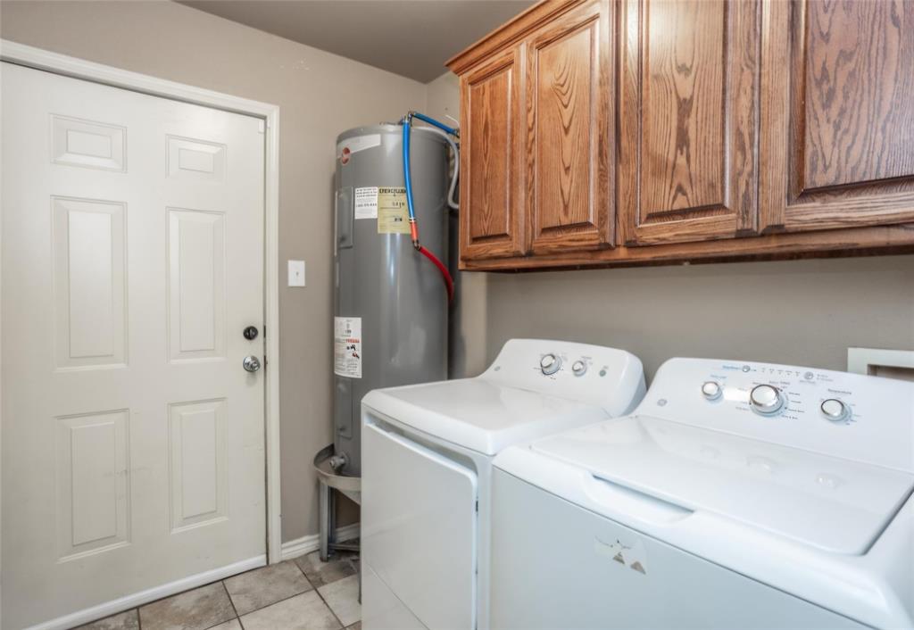Utility area featuring elevated stained wood cabinetry, ceramic tile flooring, and a six-panel door