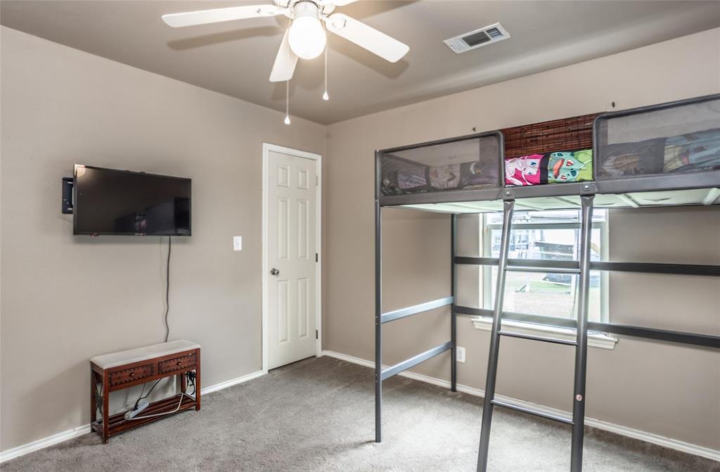 Neutral-toned interior room featuring wall-to-wall carpeting, a multi-blade ceiling fan with integrated lighting, and a six-panel interior door