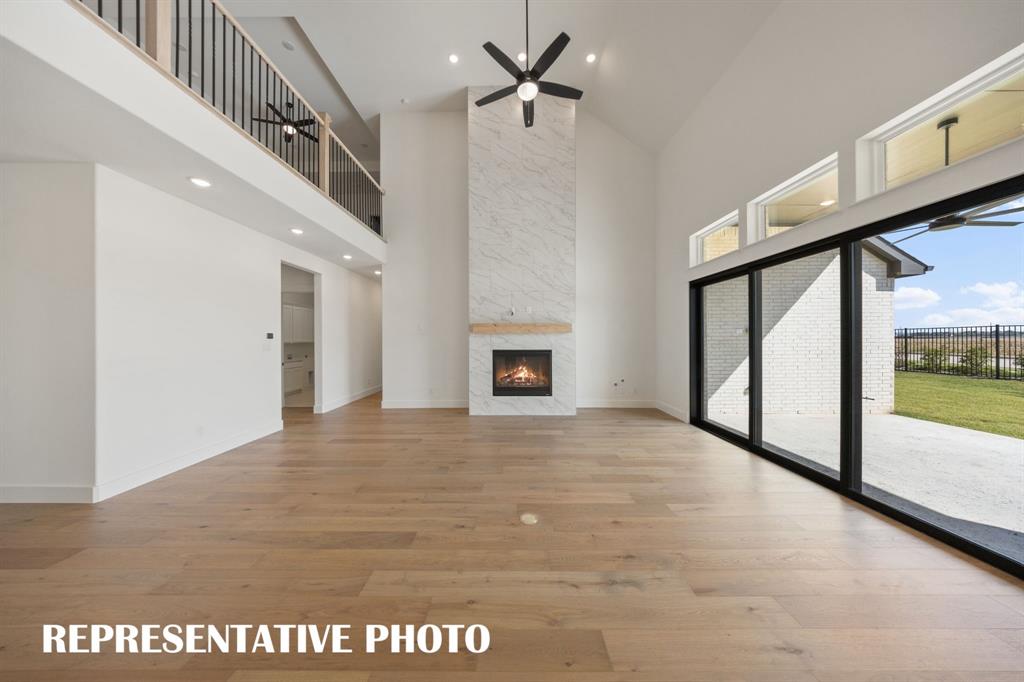 Featuring soaring ceilings, a cozy fire place and full wall slider, this family room is the ideal space for the family to gather.  REPRESENTATIVE PHOTO