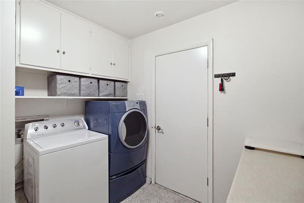 Conveniently located just off the kitchen, the dedicated laundry room offers space for a full-size washer and dryer, overhead cabinetry, open shelving, and additional counter space for folding clothes or organizing household essentials.