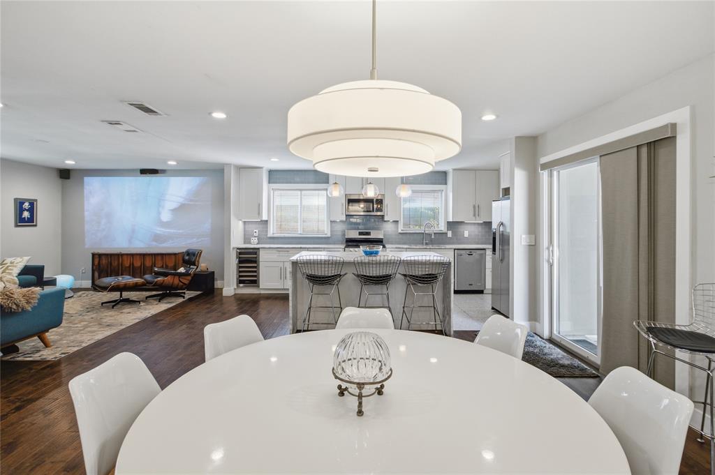 From the dining area, the home's thoughtful layout comes into focus, with the kitchen's generous island, abundant cabinetry, and stainless steel appliances framed by two windows. Sliding glass doors provide easy access to the outdoors, while the adjoining living room offers a comfortable place to unwind with a favorite movie. The open design creates a bright, connected environment without sacrificing the individual character of each space.