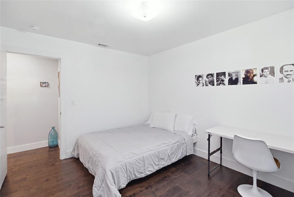 This secondary bedroom features rich, dark flooring, neutral walls, and space for both sleeping and studying or working. Its simple, versatile layout makes it easy to personalize for a variety of needs.