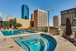 Rooftop swimming pool and spa featuring stone decking, tile accents, and an urban skyline backdrop