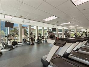 Fitness center featuring expansive floor-to-ceiling windows, rubberized flooring, and multiple ceiling-mounted light panels