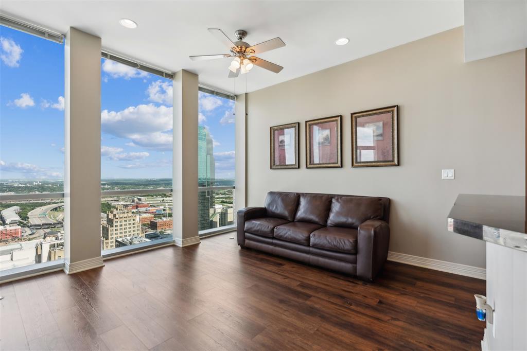 Floor-to-ceiling windows, wood-finish flooring, recessed lighting, and a multi-blade ceiling fan with integrated lighting