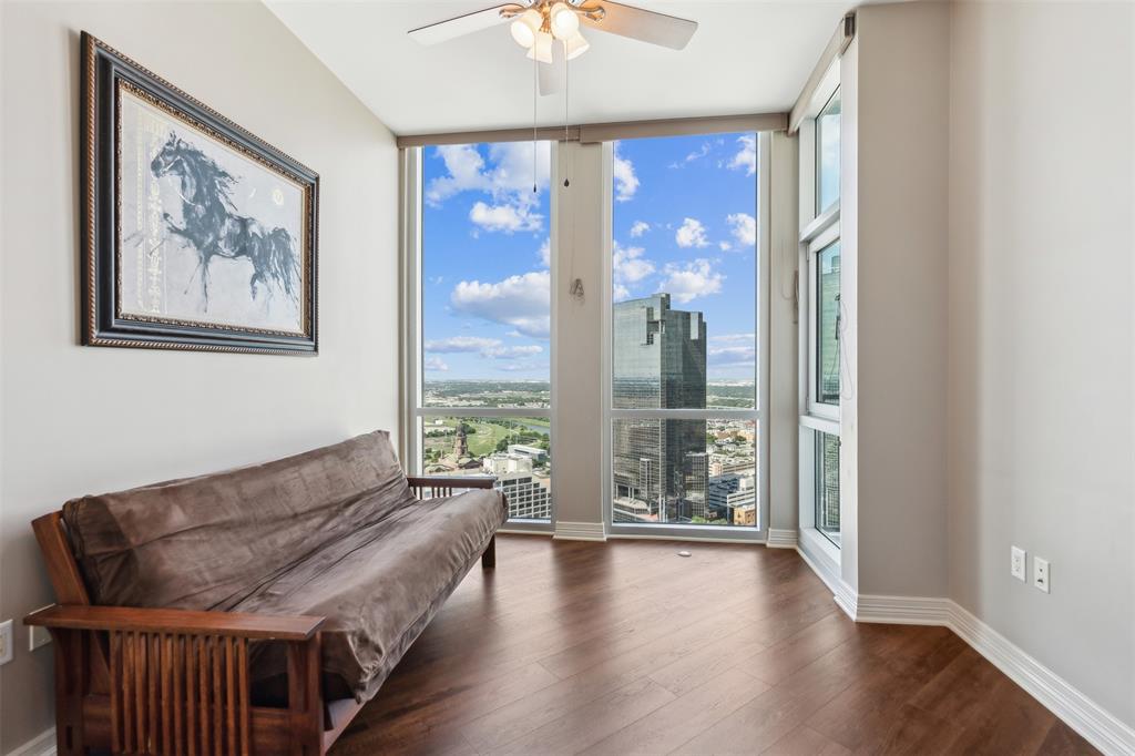 Floor-to-ceiling windows, wood-finish flooring, and a ceiling-mounted light fixture with fan