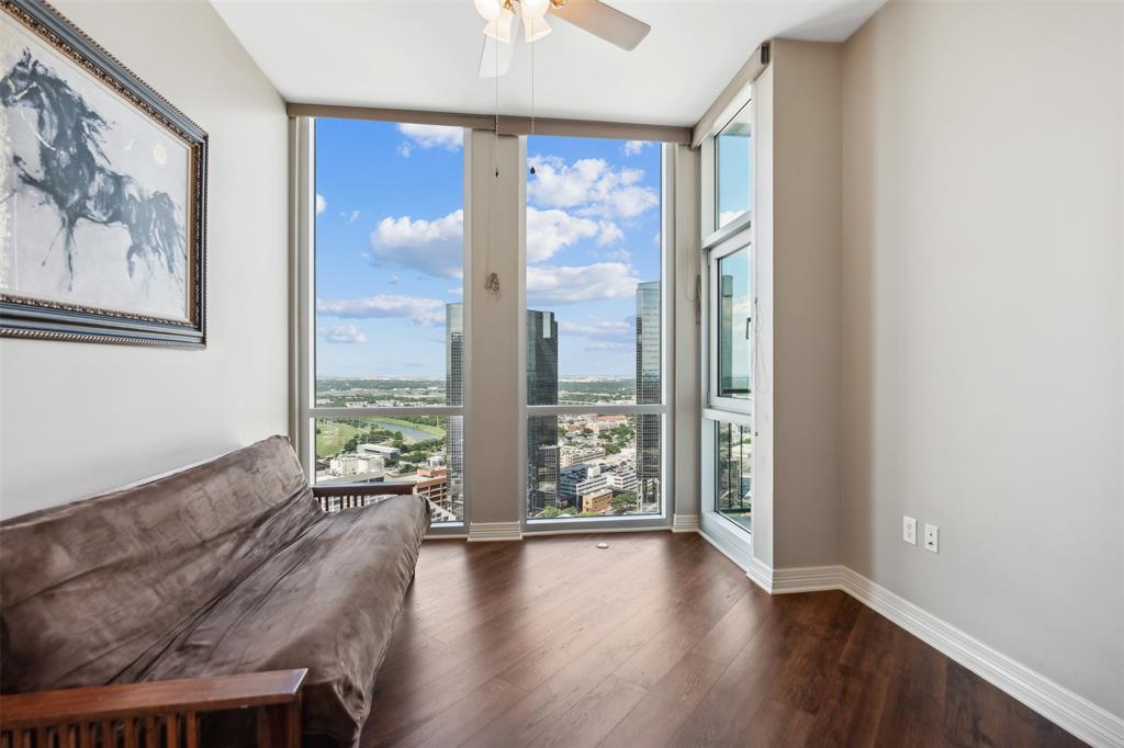 Floor-to-ceiling windows featuring urban landscape scenery, wood-finish flooring, and a ceiling-mounted light fixture