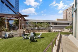 Elevated terrace featuring a manicured lawn, a stone-clad fire pit, a structural timber-frame pergola, and metal safety railings