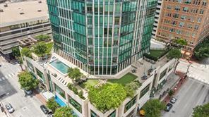 High-rise tower featuring a glass facade, expansive terrace with an outdoor swimming pool, integrated green space, and manicured landscaping