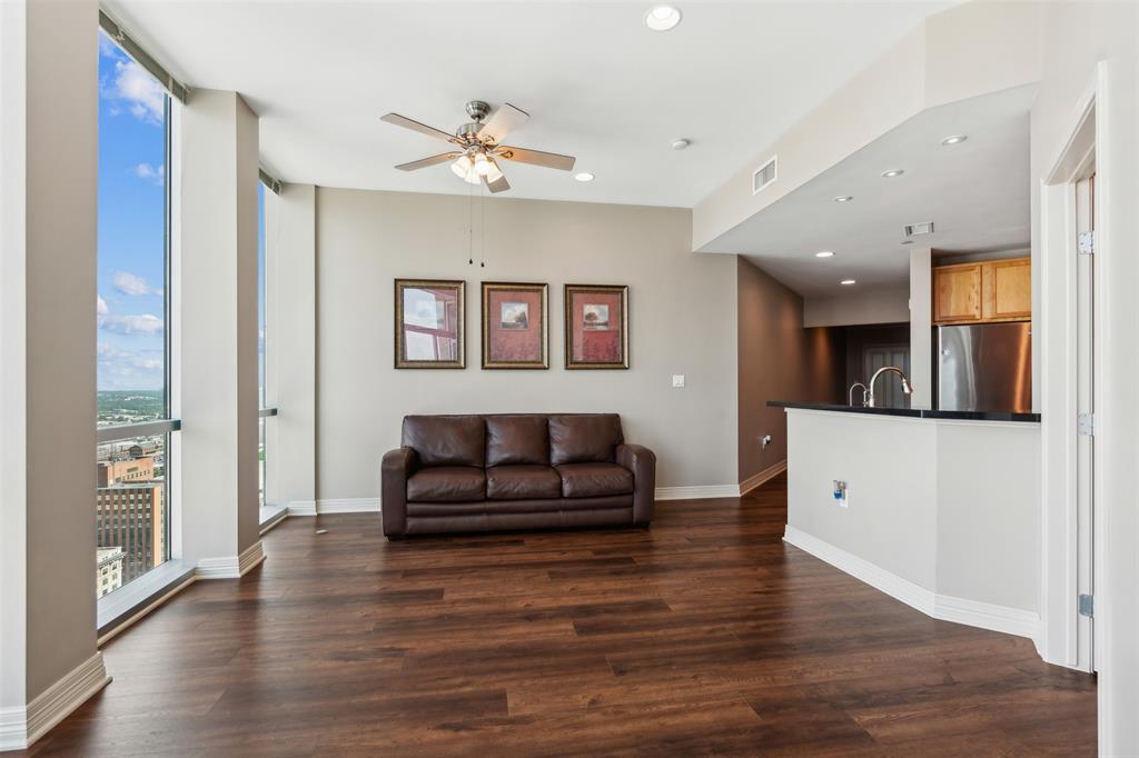 Floor-to-ceiling windows, wood-finish flooring, recessed lighting, ceiling fan, and kitchen peninsula with a dark countertop