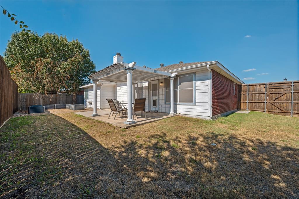 Rear exterior featuring a covered pergola with column supports, concrete patio, red brick and siding facade, and enclosed wooden privacy fencing
