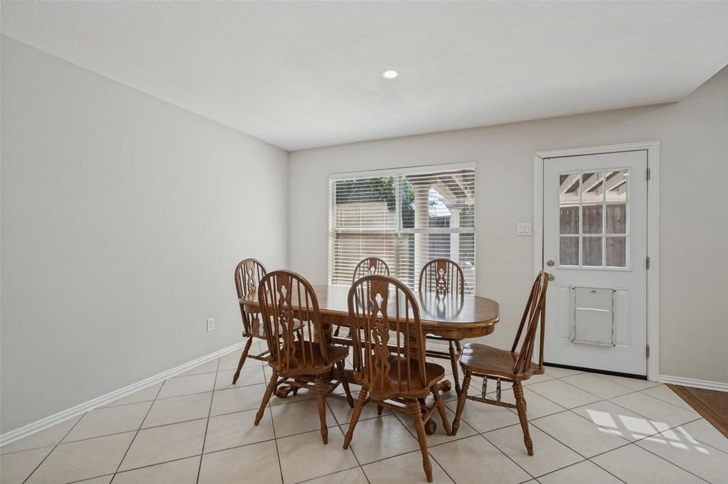 Dining space featuring neutral wall tones, large-format diagonal tile flooring, a recessed ceiling light, and a single-light exterior door with glass pane detailing