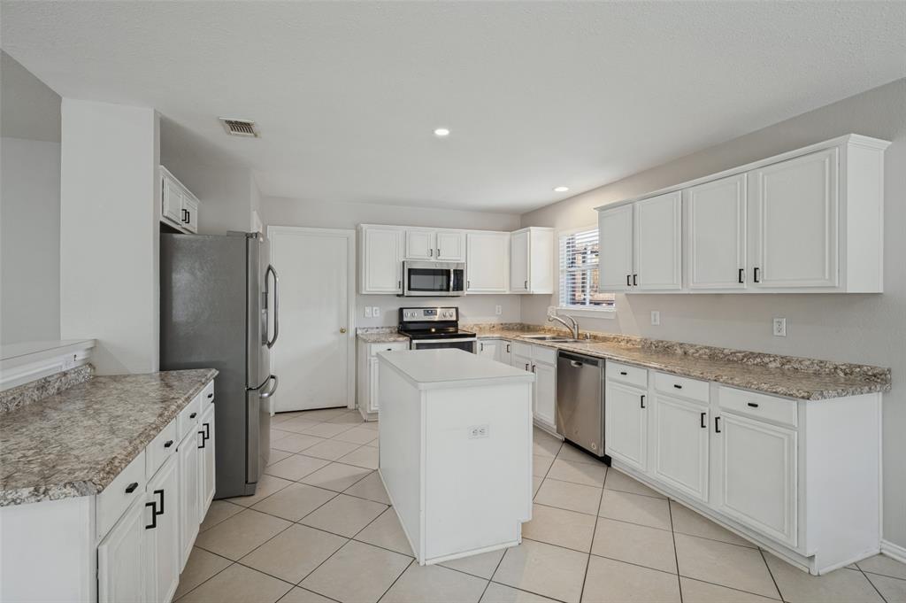 Kitchen featuring white cabinetry, stone-patterned laminate countertops, a central island, stainless steel appliances, and tile flooring