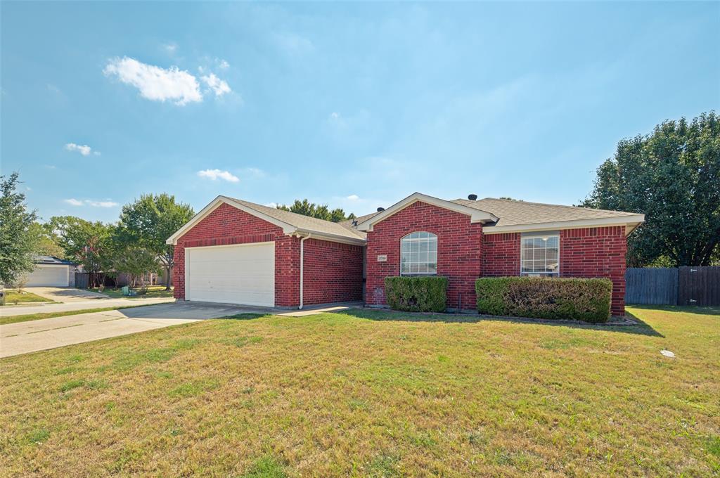 Single-story brick exterior featuring an attached two-car garage, arched window, and low-pitched roofline